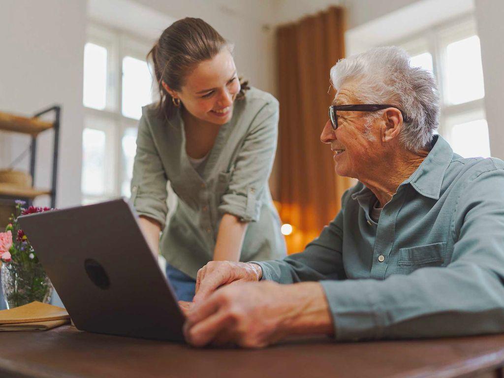 Bild: Angehörige zeigt ihrem älteren Vater etwas am Laptop